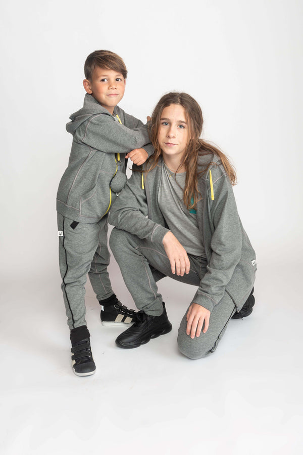 Grey sensory-friendly hoodie designed for kids with sensory sensitivity, including those with autism, ADHD, or sensitive skin. This soft hoodie is customizable with various fidget options for sensory relief and stress reduction. The design is smooth and comfortable, aiming to provide a soothing experience for children who benefit from sensory input.